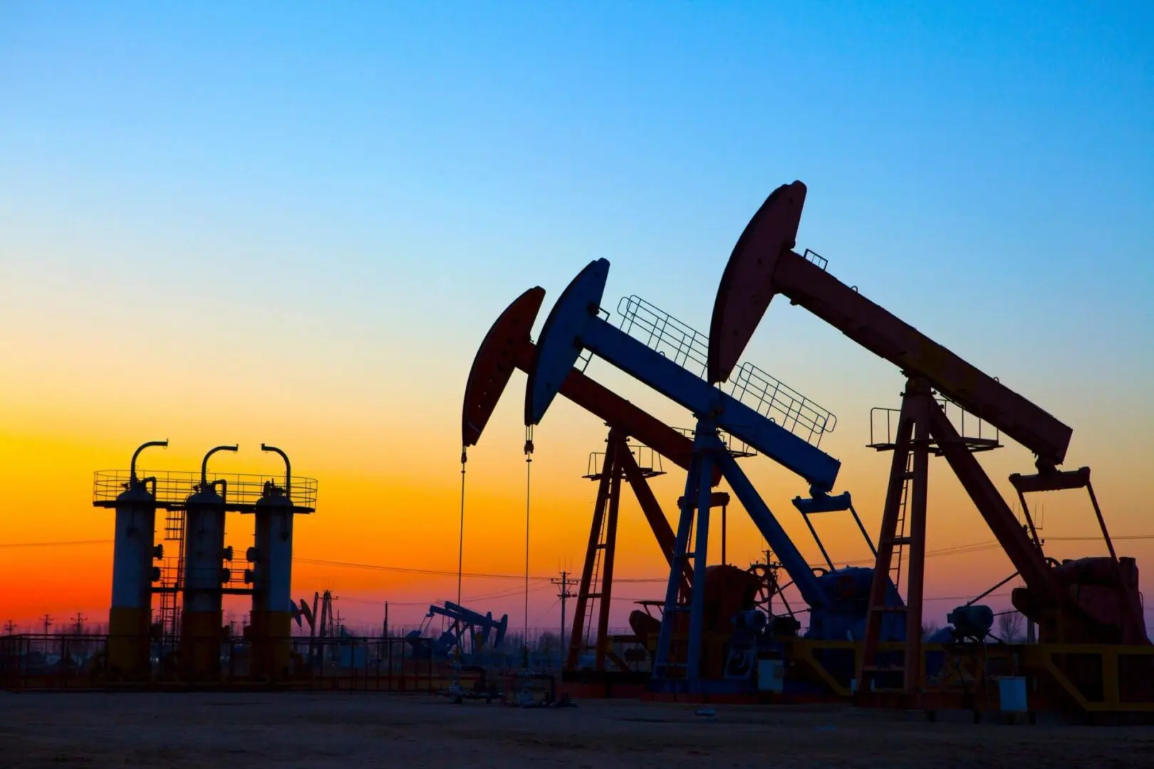 A group of oil pumps in the middle of an open field.