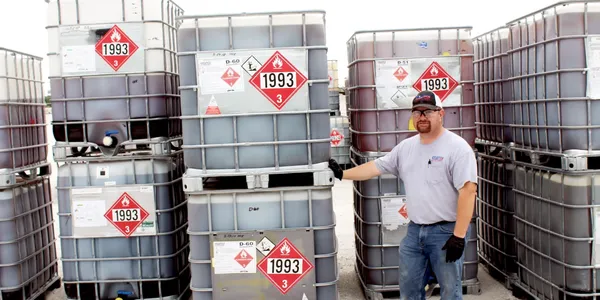 A man standing next to a stack of barrels.